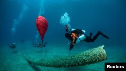 FILE - A diver inflates a lifting bag attached to remains of a fish farm on the seabed, near the island of Ithaca, Greece, June 10, 2021. (Cor Kuyvenhoven/Ghost Diving/Handout via Reuters) 