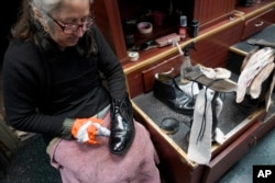 Bertha Gomez menyemir sepatu pelanggan di Alpha Shoe Repair Corp. di New York, 3 Februari 2023. Jasa semir sepatu kini menjadi lebih langka, dan banyak stan telah menghilang di seluruh AS. (AP / Mary Altaffer)