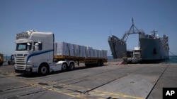 FILE - Trucks arrive loaded with humanitarian aid at the U.S.-built floating pier before reaching the beach on the coast of the Gaza Strip, June 25, 2024.