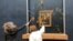 This image grab taken from AFPTV footage shows two environmental activists from the collective dubbed "Riposte Alimentaire" (Food Retaliation) hurling soup at Leonardo Da Vinci's "Mona Lisa" painting, at the Louvre museum in Paris, Jan. 28, 2024. 