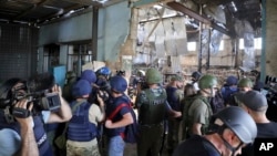 FILE - Journalists visit the destroyed barracks at the Russian-controlled Olenivka prison holding Ukrainian POWs in eastern Ukraine, Aug. 10, 2022. Russia blamed Ukraine at the time but interviews with survivors and an internal U.N. analysis point to Russia as the culprit. 