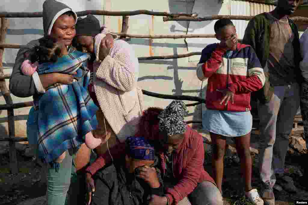 Residents react as they witness members of the Forensics Pathology Services (not seen) remove the bodies of two minors killed after a fire gutted an informal settlement in Fleurof, West of Johannesburg, South Africa, Sept. 3, 2023. 