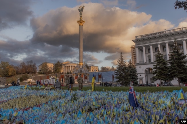 Pedestrians wearing military uniforms walk past flags bearing symbols and colors of Ukraine that commemorate the country's fallen soldiers at Independence Square in Kyiv, on Oct. 23, 2023, amid the Russian invasion of Ukraine.