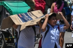 Seorang pelajar menggunakan amplop untuk melindungi dirinya dari terik matahari di Manila pada 2 April 2024. (Foto: AFP)