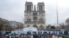People stand in front of Notre-Dame de Paris Cathedral during the reconstruction work on the Ile de la Cite in Paris, on Dec. 8, 2023, one year to the day before the cathedral, which was ravaged by fire in 2019, is due to reopen. 