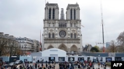 People stand in front of Notre-Dame de Paris Cathedral during the reconstruction work on the Ile de la Cite in Paris, on Dec. 8, 2023, one year to the day before the cathedral, which was ravaged by fire in 2019, is due to reopen. 