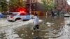 A man stands in floodwater as he works to clear a drain in the Brooklyn borough of New York, Sept. 29, 2023. 