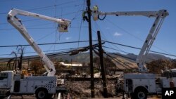FILE - Electric crews work on power lines in the aftermath of a devastating wildfire in Lahaina, Hawaii, Aug. 17, 2023.