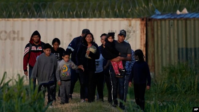 FILE - Migrants walk past a barrier after they crossed the Rio Grande and entered the US from Mexico, Oct. 19, 2023, in Eagle Pass, Texas.