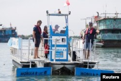 Pekerja mengoperasikan kapal pengumpul sampah bernama Mobula 8 di pelabuhan Benoa di Denpasar, Bali, 21 Maret 2023. (REUTERS/Johannes P. Christo)