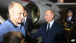 Russian President Vladimir Putin, right, greets Artem Dultsev, left, upon arrival of freed Russian prisoners at Vnukovo government airport outside Moscow, Aug. 1, 2024. (Mikhail Voskresensky, Sputnik, Kremlin pool photo via AP)