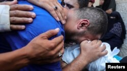 A Palestinian father grieves over the body of his son who was killed in an Israeli strike, amid the Israel-Hamas conflict, at Al-Aqsa Martyrs Hospital in Deir Al-Balah in the central Gaza Strip, July 9, 2024.