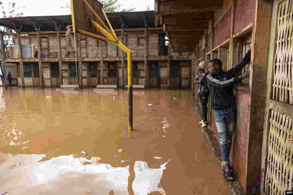 People who live in the Mathare slum use the wall to cross a flooded school field, following heavy rains in the Kenyan capital, Nairobi.