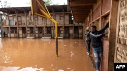 Residents of Mathare slum use the wall to cross a flooded school field, following heavy downpour in the Kenyan capital, Nairobi.