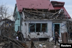 Local residents walk next to their house that was damaged during a Russian missile and drone strike, amid Russia's attack on Ukraine, in Kamianske, Dnipropetrovsk region, Ukraine, March 29, 2024.