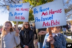 Noa Friedan, 13, left, and Eila Friedan, 11, of Philadelphia, hoist signs saying "Pro Israel, Anti Hamas, Pro Peace, Anti Bibi" while rallying on the National Mall in Washington to support Israel, Nov. 14, 2023.