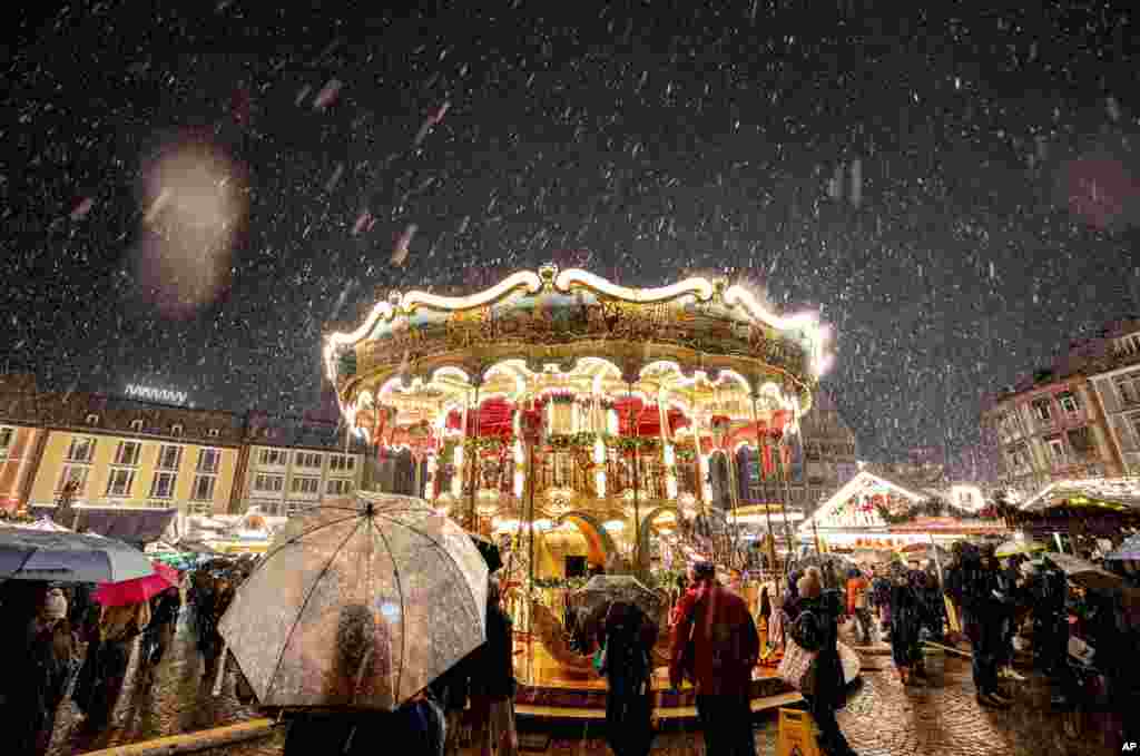 Snow falls as the traditional Christmas market with the merry-go-round was opened in Frankfurt, Germany. (AP Photo/Michael Probst)