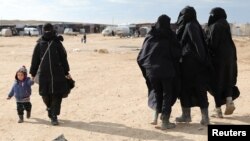 FILE - A woman holds a child's hand in the al-Hol camp, Syria, Jan. 8, 2020. After U.S.-backed and Kurdish-led fighters defeated the Islamic State group in Syria in March 2019, thousands of IS fighters and their families were taken to al-Hol.