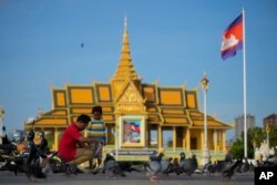 FILE - A Cambodian man with his daughter feeds pigeons outside the royal palace in Phnom Penh, Cambodia, Thursday, Nov. 10, 2022.