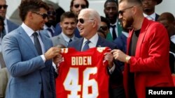 Presiden AS Joe Biden memegang kaos jersey klub sepak bola AS, Kansas City Chief, saat tim tersebut mengunjungi Gedung Putih untuk merayakan kemenangan di turnamen Super Bowl LVII, di Washington, 5 Juni 2023. (Foto: Evelyn Hockstein/Reuters)