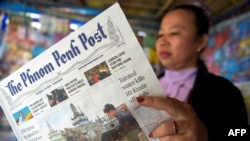 FILE - A Cambodian vendor reads The Phnom Penh Post at her newstand in Phnom Penh on May 7, 2018.