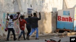 Residents walk past a the body of a man during clashes between police and gang members in Port-au-Prince, Haiti, Feb. 29, 2024.