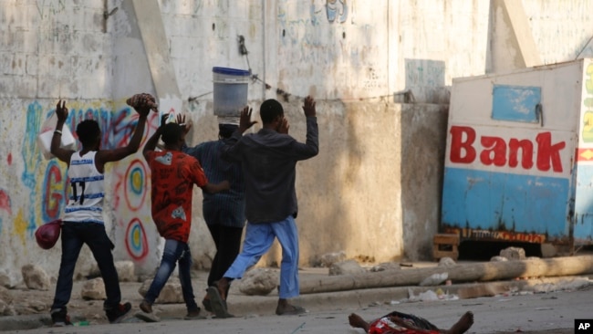 Residents walk past a the body of a man during clashes between police and gang members in Port-au-Prince, Haiti, Feb. 29, 2024.