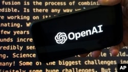 FILE - The OpenAI logo appears on a phone in front of a screen showing part of the company website, Nov. 21, 2023, in New York. Newsroom leaders are asking how artificial intelligence can be ethically relied upon by an industry whose credibility depends on trust. 