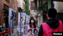 Seorang relawan salah satu parpol mempromosikan kandidat jagoannya kepada warga Hong Kong dalam pemilihan Dewan Distrik di Hong Kong pada 10 Desember 2023. (Foto: Reuters/Tyrone Siu)