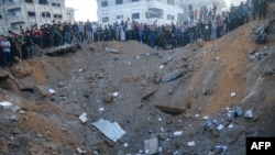 Palestinians stand on the edge of a crater after an Israeli strike in Rafah in the southern Gaza Strip, Dec. 3, 2023, amid continuing battles between Israel and Hamas. 