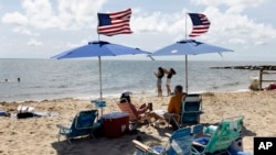 FILE - People fly the American flag on their beach umbrellas, Aug. 30, 2024, in Dennis Port, Mass. 