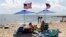 FILE - People fly the American flag on their beach umbrellas, Aug. 30, 2024, in Dennis Port, Mass. 