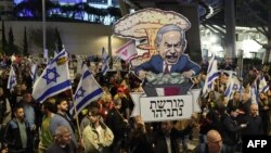 Protesters carry placards during a gathering called for by relatives of Israeli hostages held in Gaza since the October 7 attacks by Hamas militants, in Tel Aviv on March 9, 2024.