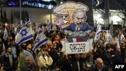 Protesters carry placards during a gathering called for by relatives of Israeli hostages held in Gaza since the October 7 attacks by Hamas militants, in Tel Aviv on March 9, 2024.