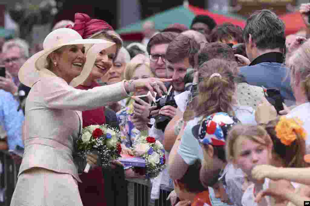 Dutch Queen Maxima, second left, and Belgium&#39;s Queen Mathilde, left, greet the crowd at the Grand Place in Brussels, Belgium.