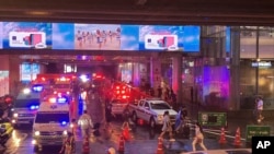 Ambulances wait outside an exit of the Siam Paragon Mall while shoppers rush out after shots are fired inside, in Bangkok, Thailand, Oct. 3, 2023.