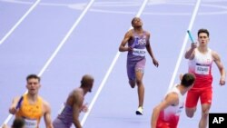 Quincy Wilson, of the United States, approaches teammate Vernon Norwood to handover the baton in a men's 4 x 400 meters relay round 1 heat at the 2024 Summer Olympics, Aug. 9, 2024, in Saint-Denis, France. 