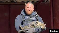 FILE - Reuters safety adviser Ryan Evans holds a cat that he found while working with a news reporting team in Niu-York, Donetsk Oblast, Ukraine, Sept. 8, 2022.