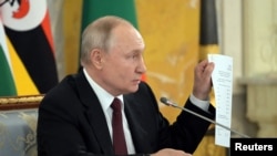 Russian President Putin shows what he says is a draft agreement with Ukraine, which was discussed in Turkey last year, during a meeting with an African delegation, June 17, 2023. (Yevgeny Biyatov/Host photo agency RIA Novosti via Reuters) 