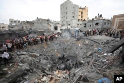 Warga Palestina memeriksa reruntuhan sebuah gedung yang hancur akibat serangan udara Israel di Deir al Balah, Jalur Gaza, 27 Oktober 2023. (Foto: Ali Mahmoud/AP Photo)