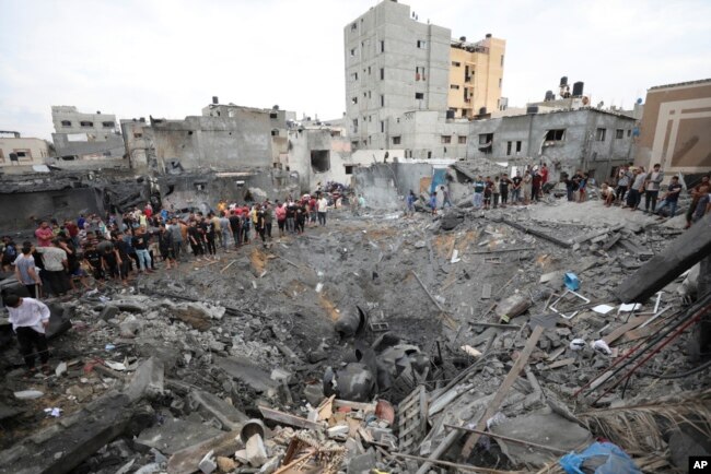 Warga Palestina memeriksa reruntuhan sebuah gedung yang hancur akibat serangan udara Israel di Deir al Balah, Jalur Gaza, 27 Oktober 2023. (Foto: Ali Mahmoud/AP Photo)