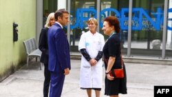 Presiden Prancis Emmanuel Macron (kedua dari kiri), bersama istrinya Brigitte Macron (kiri) disambut Direktur CHU Grenoble Monique Sorrentino (kanan) setibanya di Rumah Sakit Universitas (CHU) di Grenoble, Pegunungan Alpen Prancis, pada 9 Juni 2023. (Benoit Lagneux / POOL / AFP)