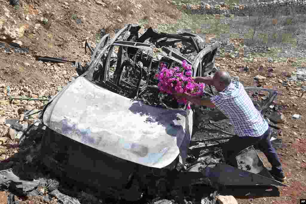 Samir Ayoub, uncle of three children who were killed by an Israeli airstrike, puts flowers on their car in the town of Ainata, a Lebanese border village with Israel in south Lebanon.