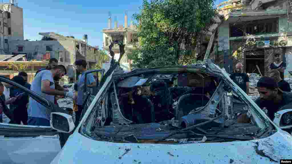 Palestinians inspect a vehicle where Al Jazeera TV said its reporter Ismail al-Ghoul and cameraman Ramy El Rify were killed in an Israeli strike, in Gaza City.