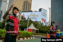 FILE - Polisi mengatur arus lalu lintas di dekat baliho bertuliskan selamat datang untuk Paus Fransiskus di Jakarta pada 2 September 2024. (Bay Ismoyo/AFP)