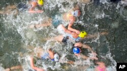 FILE - Athletes compete in the swim leg of the women's individual triathlon competition at the 2024 Summer Olympics, in Paris, France, July 31, 2024.