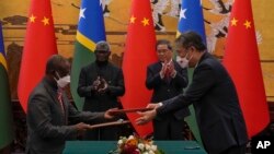 마나세 소가바레 솔로몬제도 총리(사진 뒤편 왼쪽)와 리창 중국 총리(사진 뒤편 오른쪽)가 10일 중국 베이징에서 두 나라 관리가 양국이 서명한 협정문을 주고받는 것을 보면서 손뼉 치고 있다. 