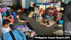 In this photo provided by the Philippine Coast Guard, stranded passengers stay at a passenger terminal after sea travel was suspended due to Typhoon Doksuri in Manila, Philippines on July 25, 2023. (Philippine Coast Guard via AP)