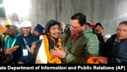 Pushkar Singh Dhami, right, Chief Minister of the state of Uttarakhand, greets a worker rescued from the site of an under-construction road tunnel that collapsed in Silkyara in the northern Indian state of Uttarakhand, India. (Uttarakhand State Department of Information and Public Relations via AP)