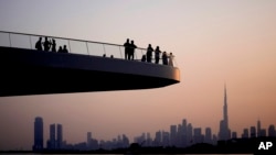 FILE - People stand on the observation deck of the Dubai Creek Harbour in Dubai, United Arab Emirates, June 18, 2023, to view the city skyline with the world's tallest tower, the Burj Khalifa. 